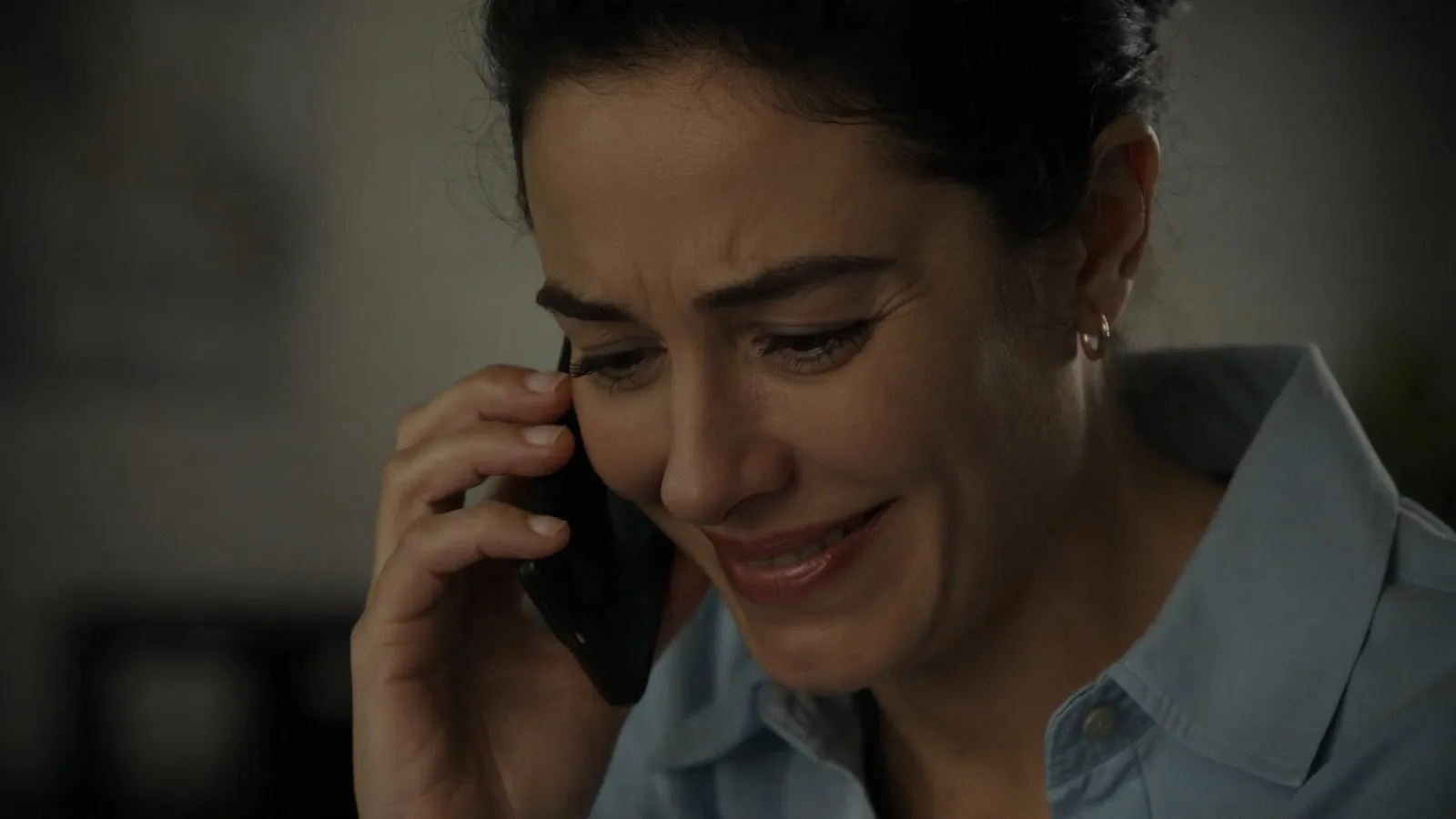 Primer plano de una mujer que habla por teléfono entre lágrimas y una sonrisa triste