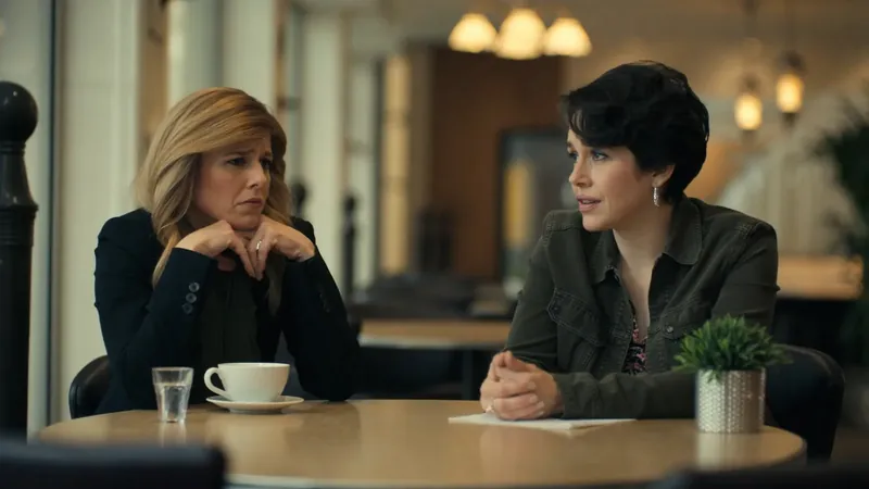 Dos mujeres sentadas frente a frente en la mesa de una cafetería, una hablando y la otra escuchando con gesto serio